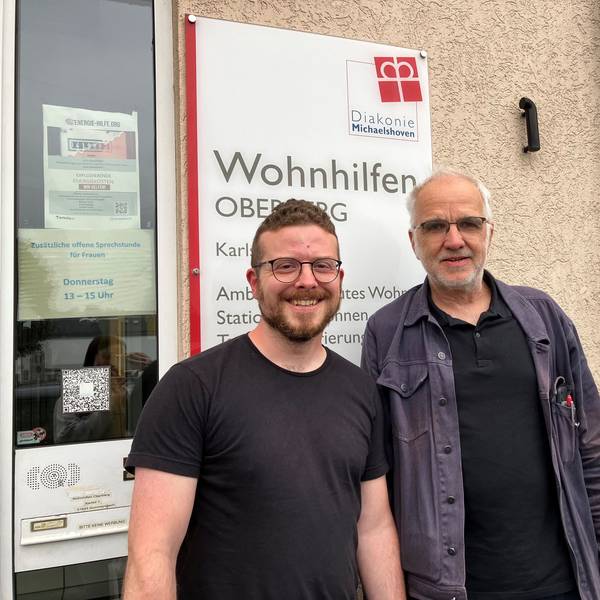 Morten Kochhäuser und Wilfried Fenner stehen gemeinsam vor dem Gebäude in Gummersbach, in dem Büros der Wohnhilfen Oberberg Mitte untergebracht sind.