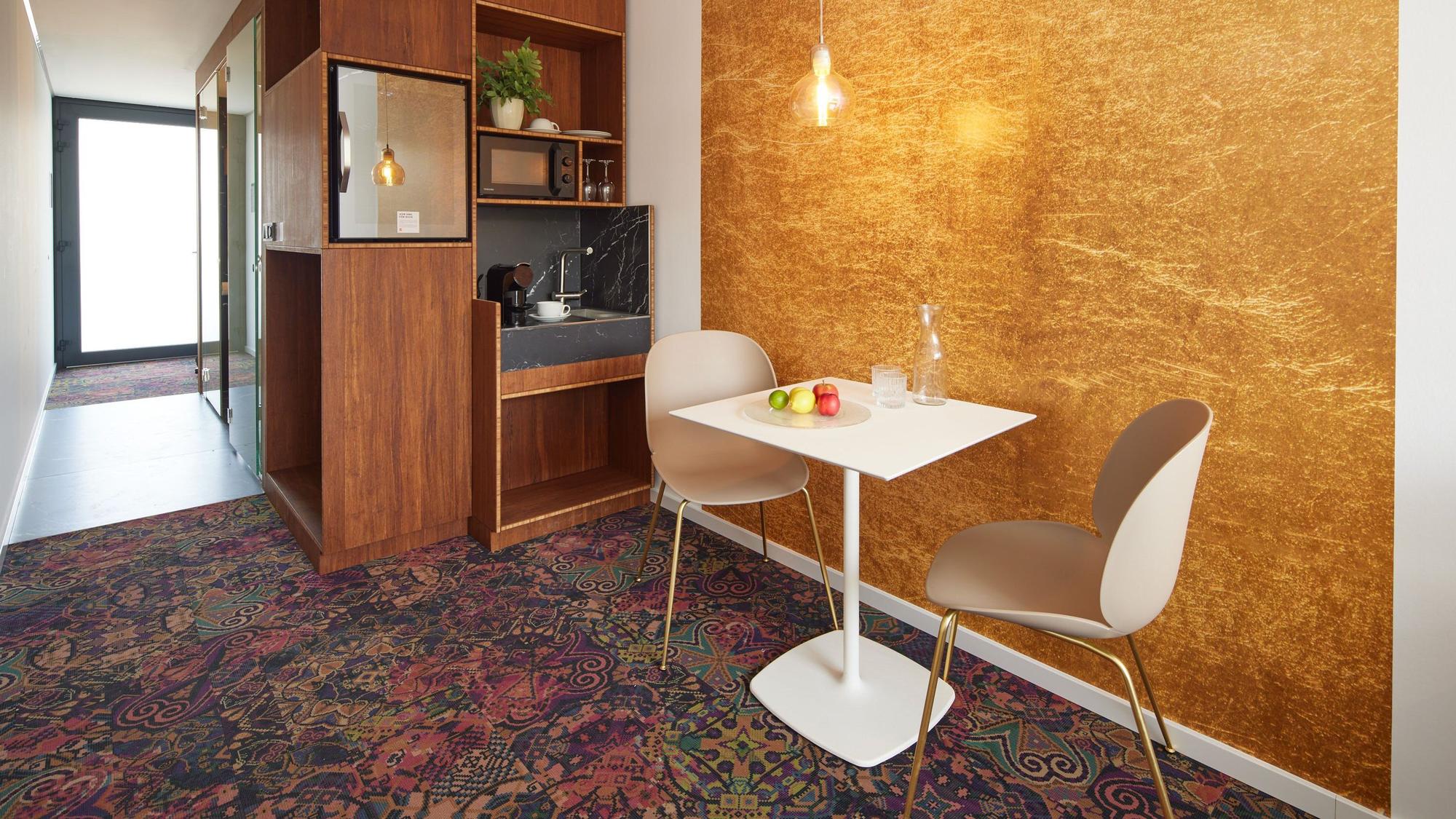 Das Bild zeigt ein Hotelzimmer mit einem kleinen Tisch und zwei Stühlen.