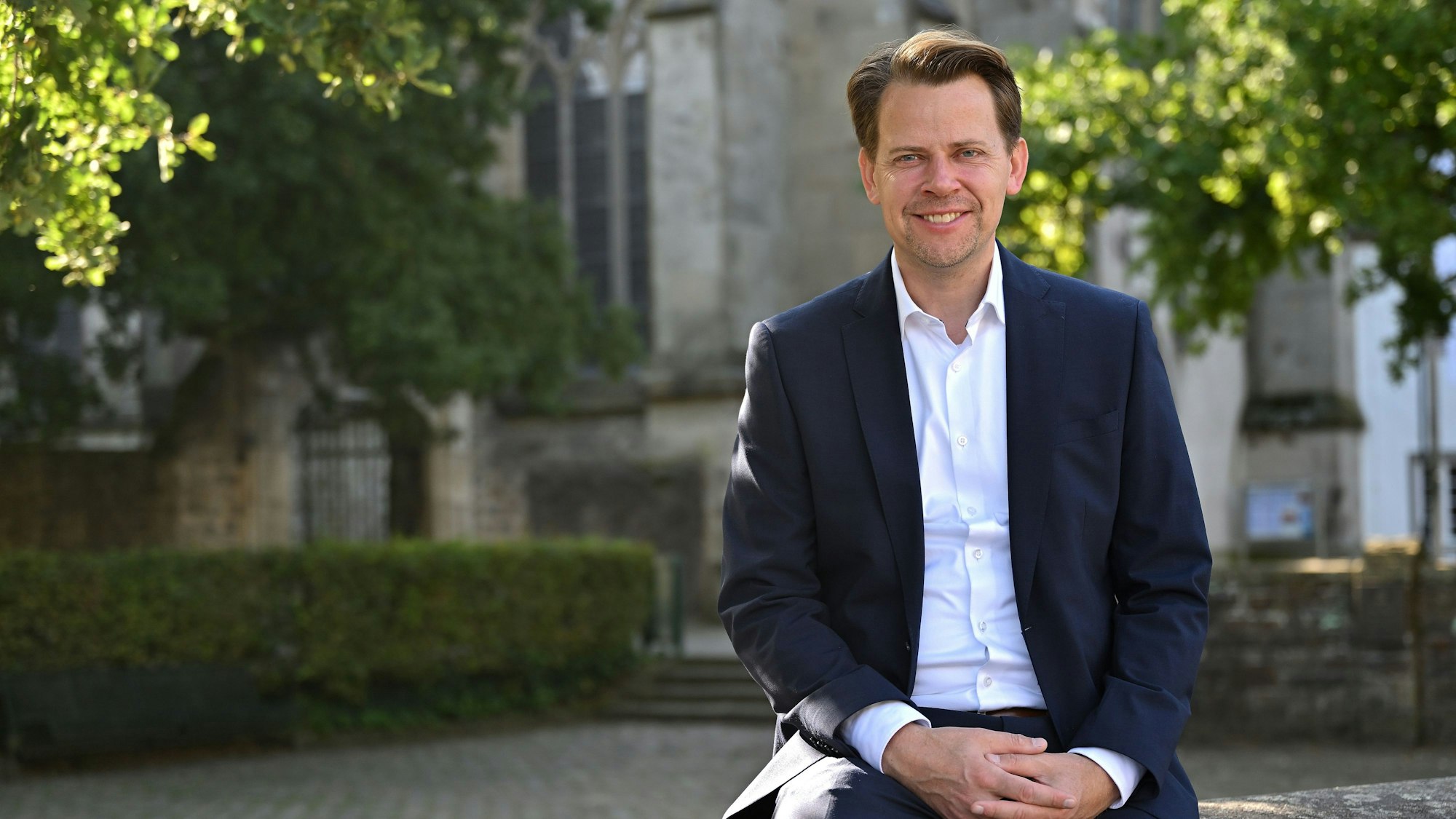 CDU-Landratskandidat Arne von Boetticher sitzt vor dem Altenberger Dom.