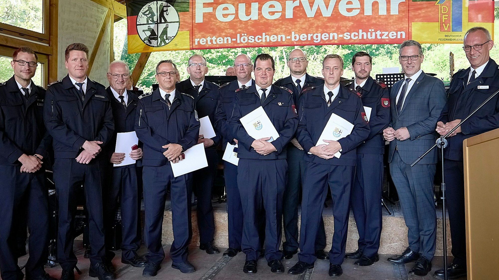 Die geehrten Feuerwehrleute haben sich vor einer Feuerwehr-Fahne zum Gruppenbild zusammengestellt.