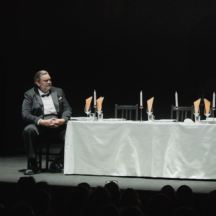 Andreas Beck sitzt im Smoking am Ende eines langen, feierlich gedeckten Tisches.