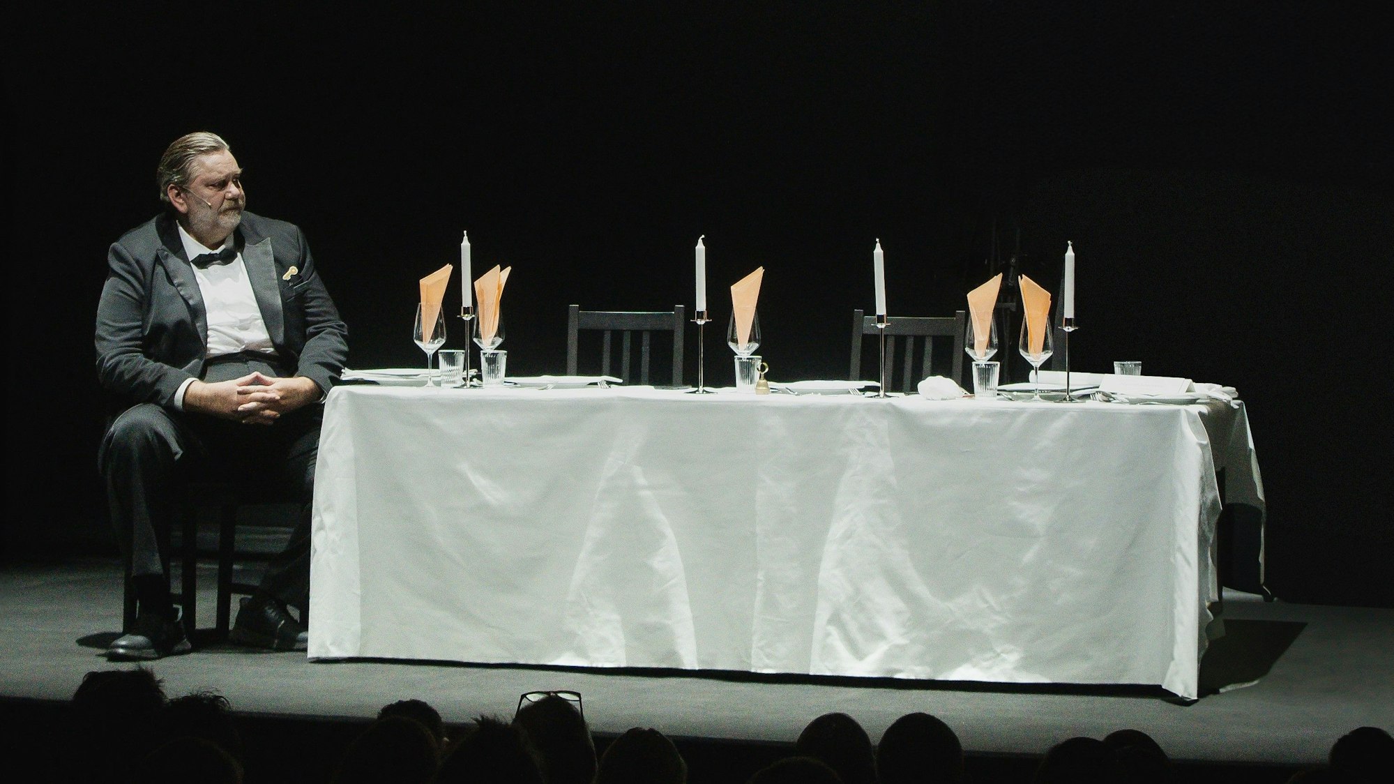 Andreas Beck sitzt im Smoking am Ende eines langen, feierlich gedeckten Tisches.