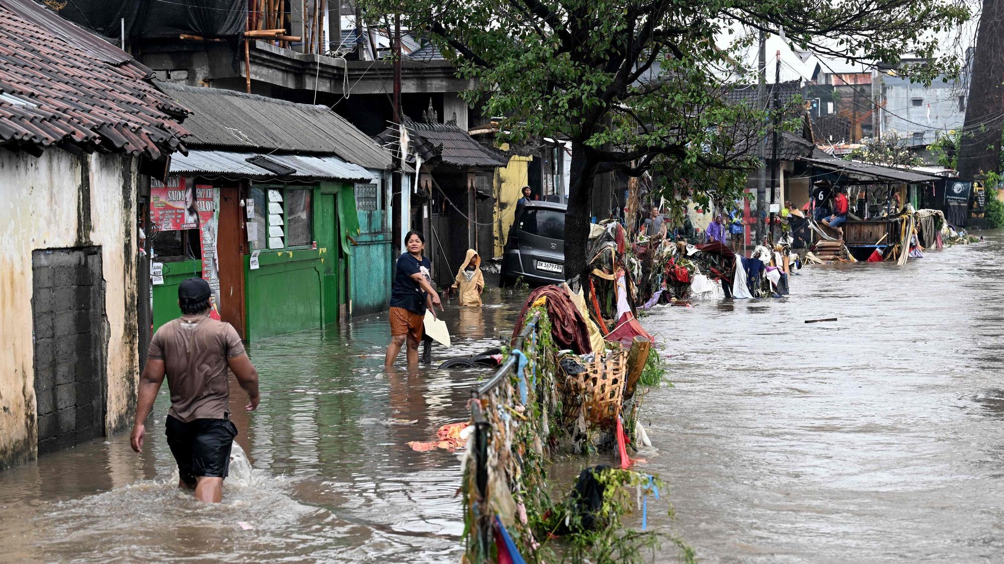 Menschen waten durch die Straßen, nachdem es in Indonesien zu Sturzfluten kam; hier in der Stadt Denpasar auf Bali.