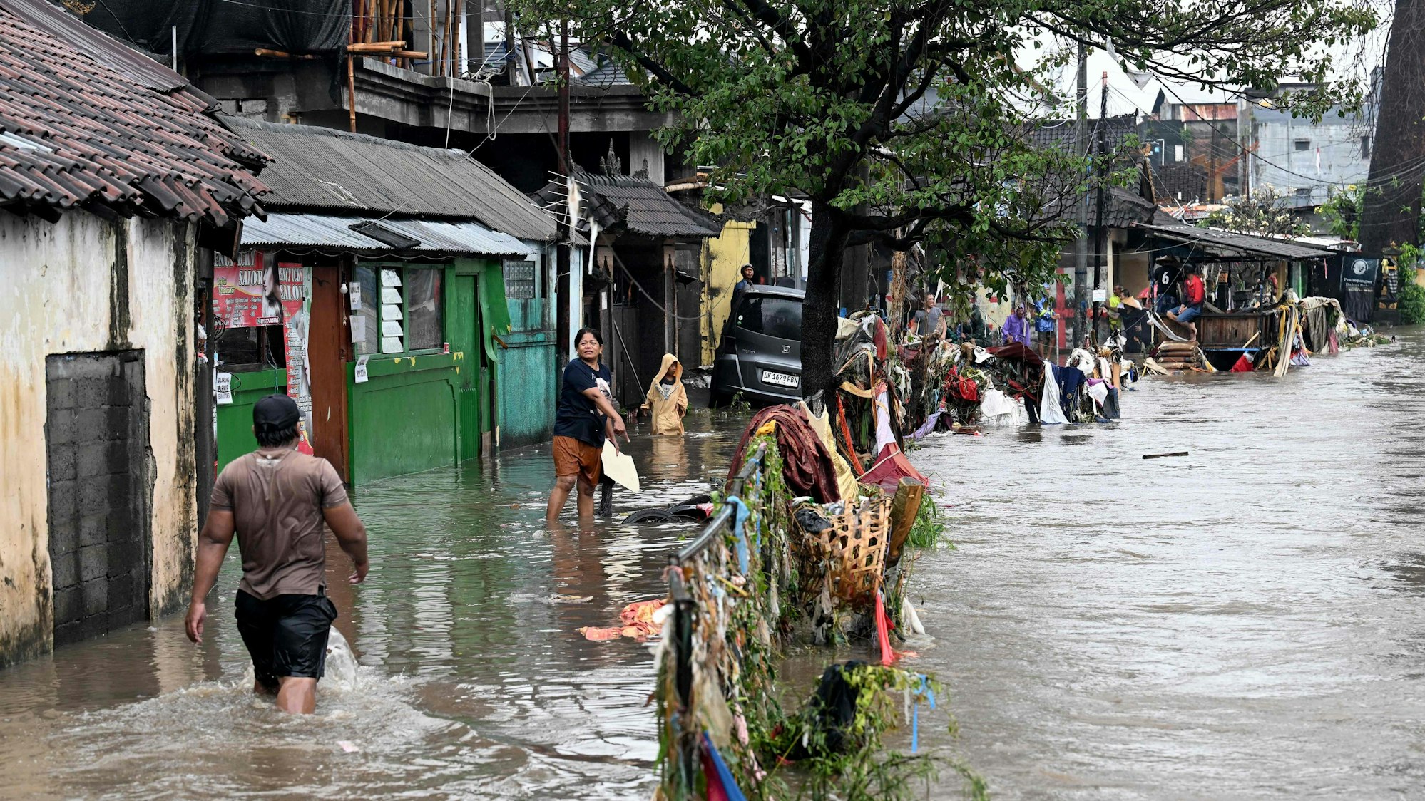Menschen waten durch die Straßen, nachdem es in Indonesien zu Sturzfluten kam; hier in der Stadt Denpasar auf Bali.