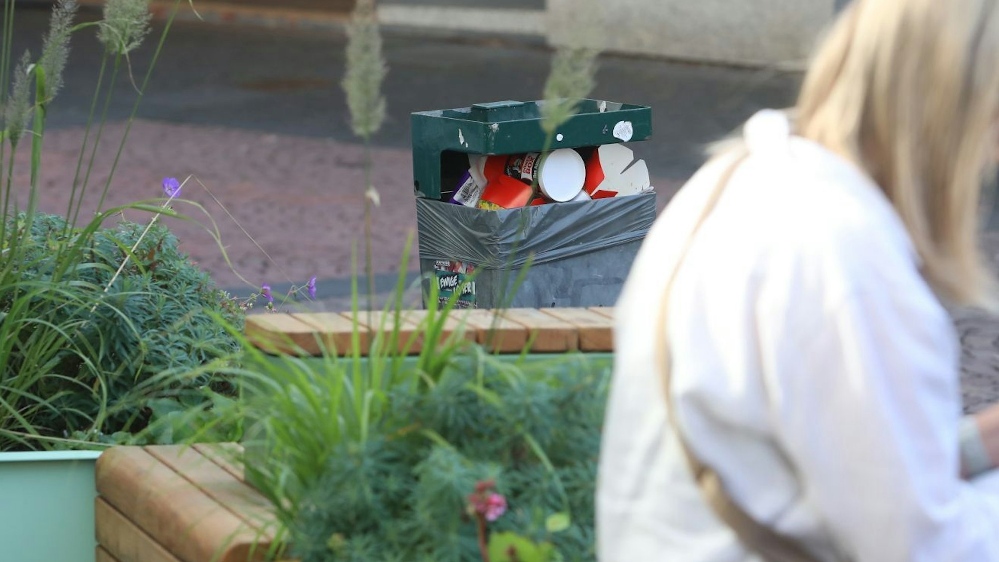 Ein voller Abfallbehälter neben einem der Bad Honnefer Stadtmöbel.