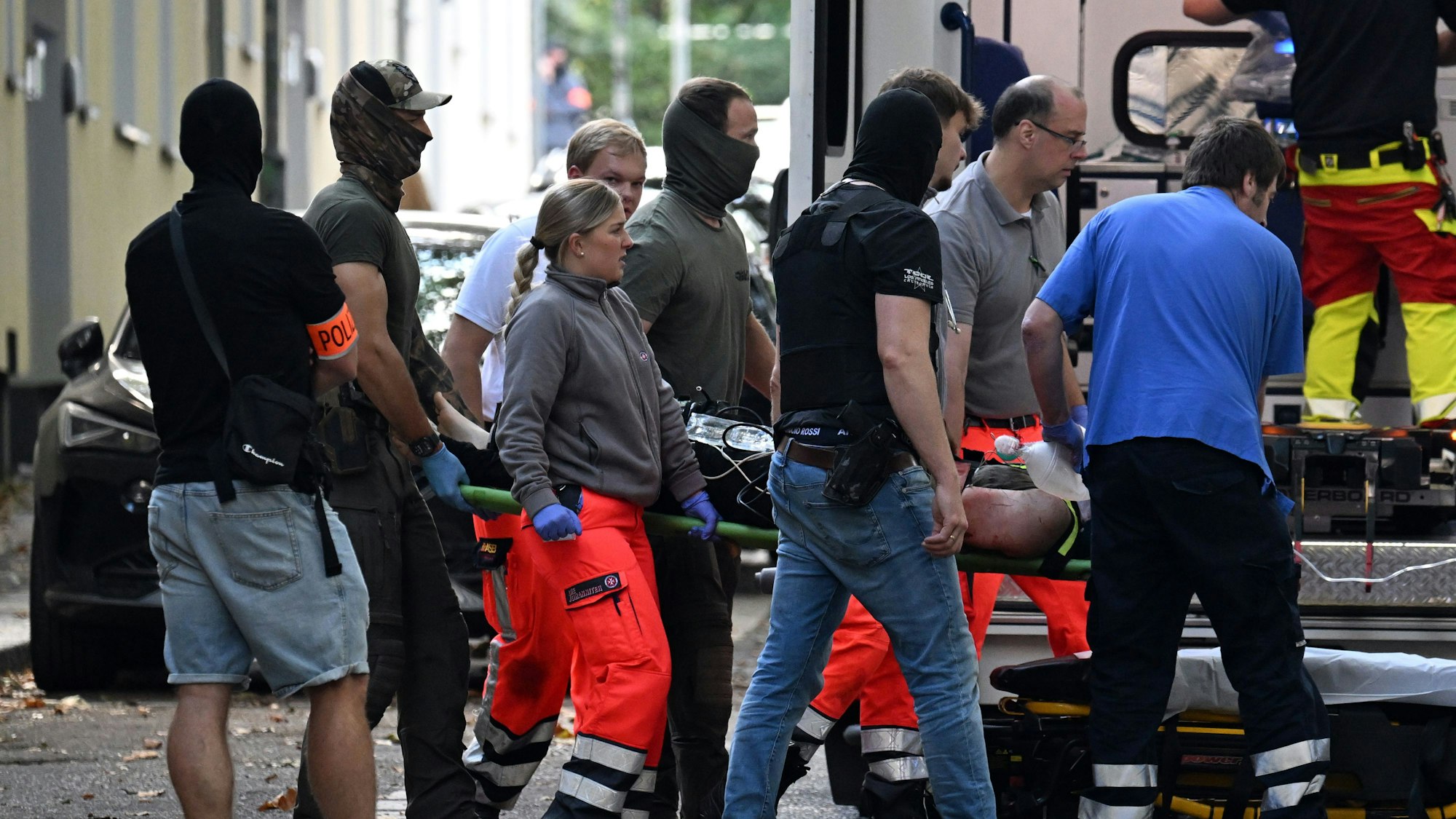 Einsatzkräfte bringen die Trage mit einer verletzten, tatverdächtigen Person zu einem Rettungswagen. Kurz nach dem Messerangriff auf eine Lehrerin an einem Berufskolleg in Essen ist die tatverdächtige Person gefasst worden.