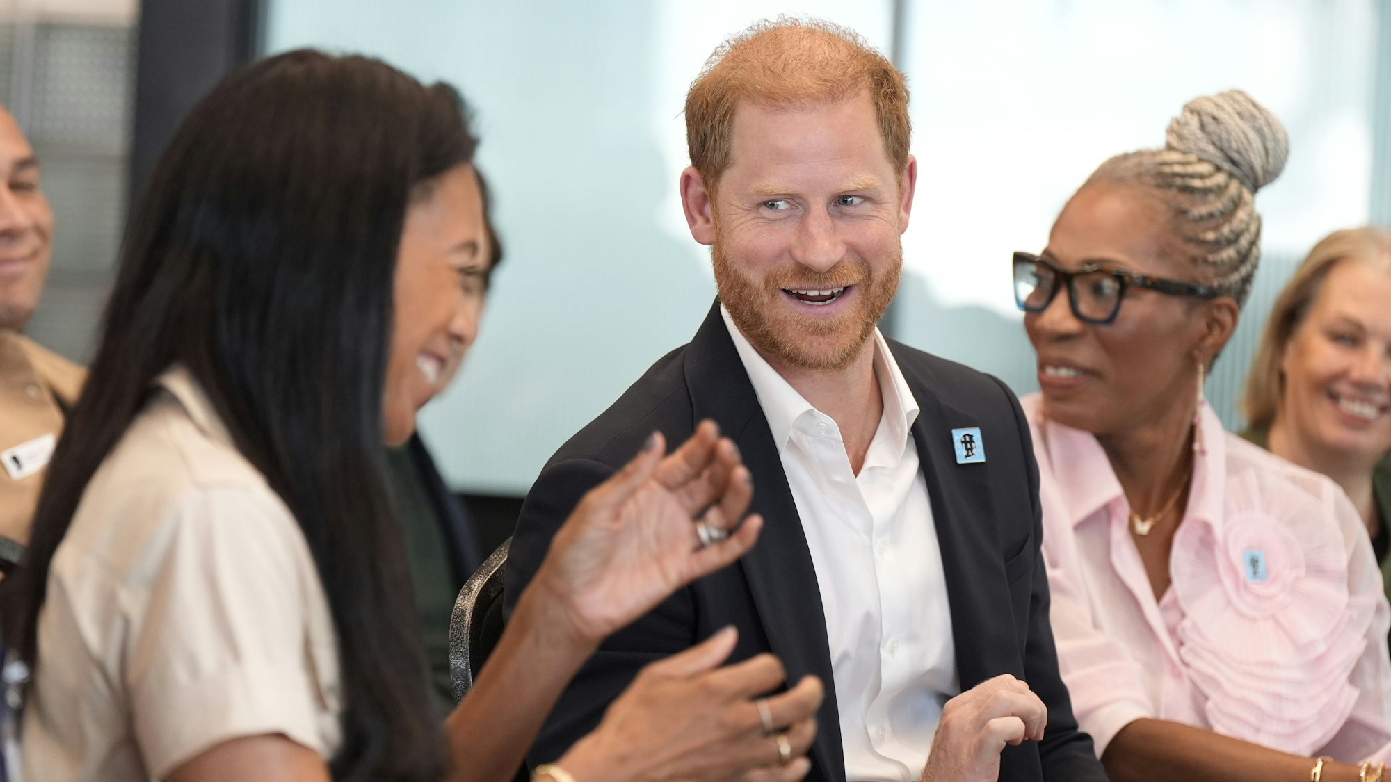 Prinz Harry lächelt und redet mit Gästen einer Diskussion.