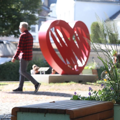 Ein Blumenbeet neben Bänken, im Hintergrund eines großes rotes Herz, das als Instagram-Spot dient