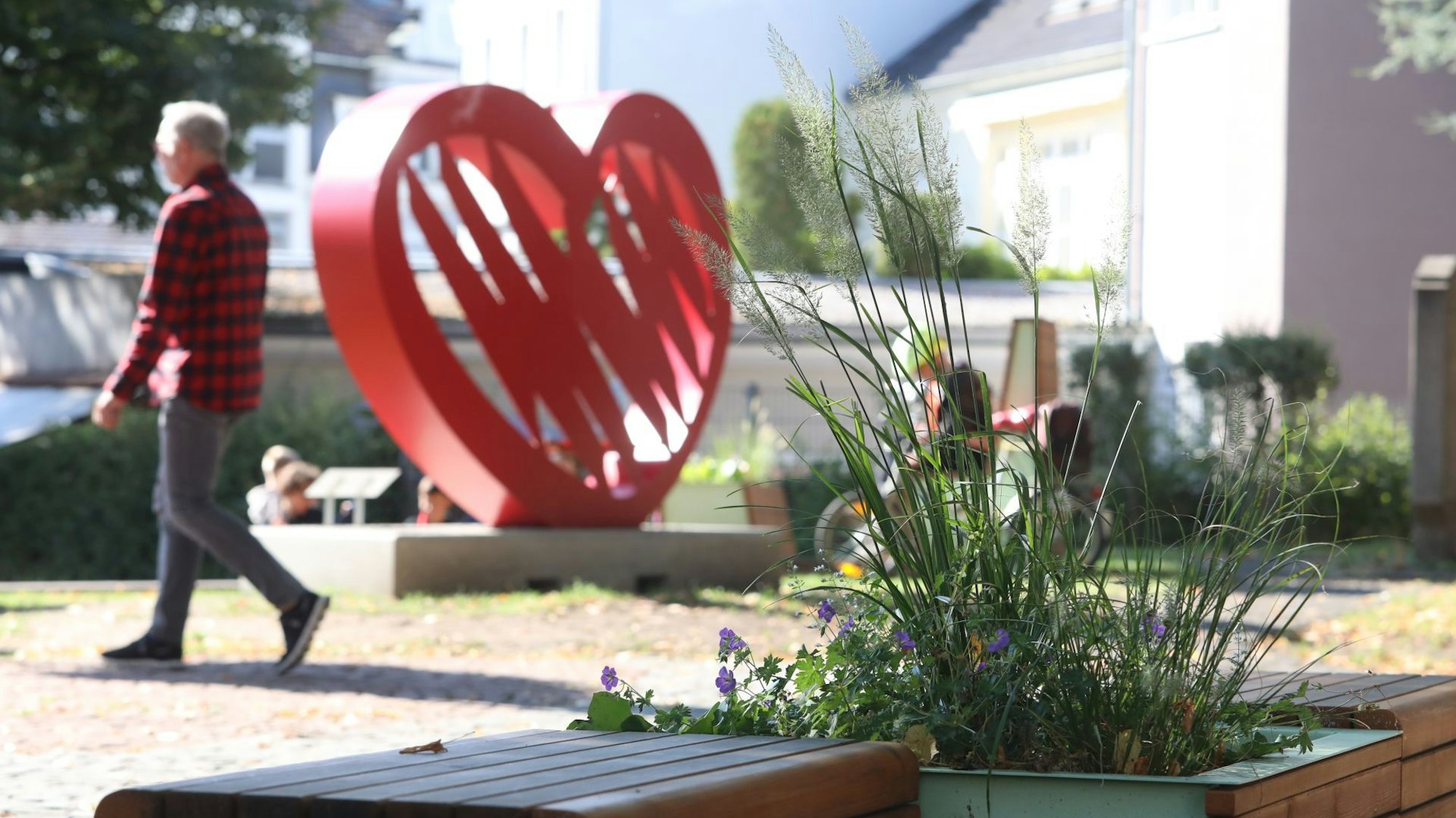 Ein Blumenbeet neben Bänken, im Hintergrund eines großes rotes Herz, das als Instagram-Spot dient