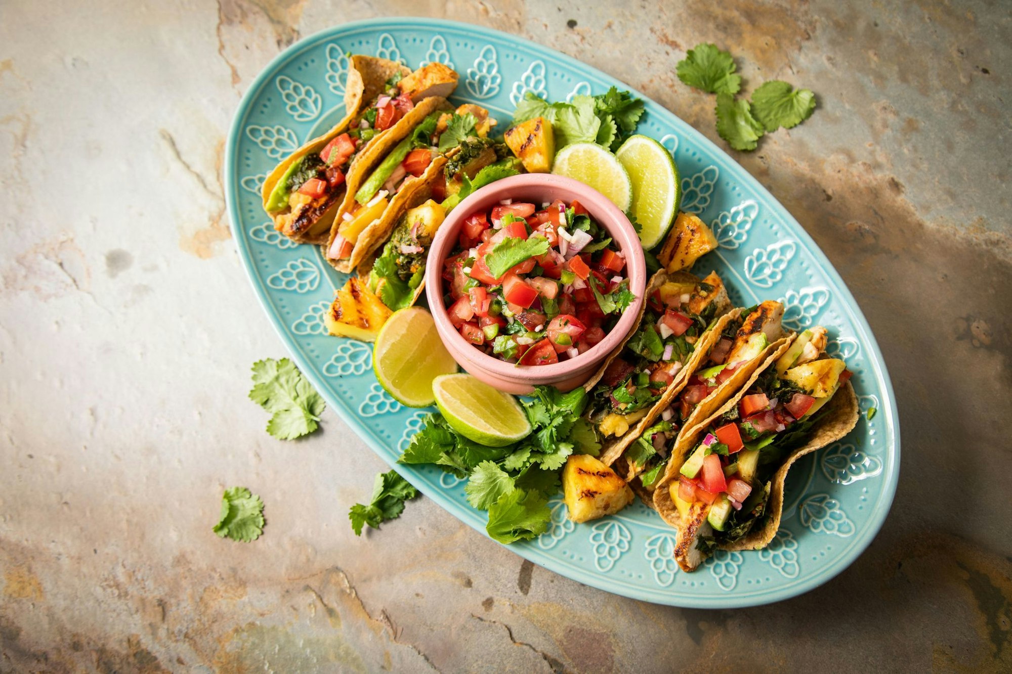 Richtig stilecht werden Hähnchen-Tacos erst mit Zugaben wie der mexikanische Tomatensalsa «Pico de Gallo», argentinischer Kräutersauce «Chimichurri», Avocado, gegrillter Ananas, Koriander und Limetten.