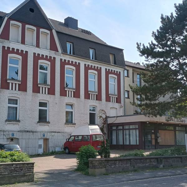 Zu sehen ist das mehrstöckige Haus, davor parken zwei Autos.