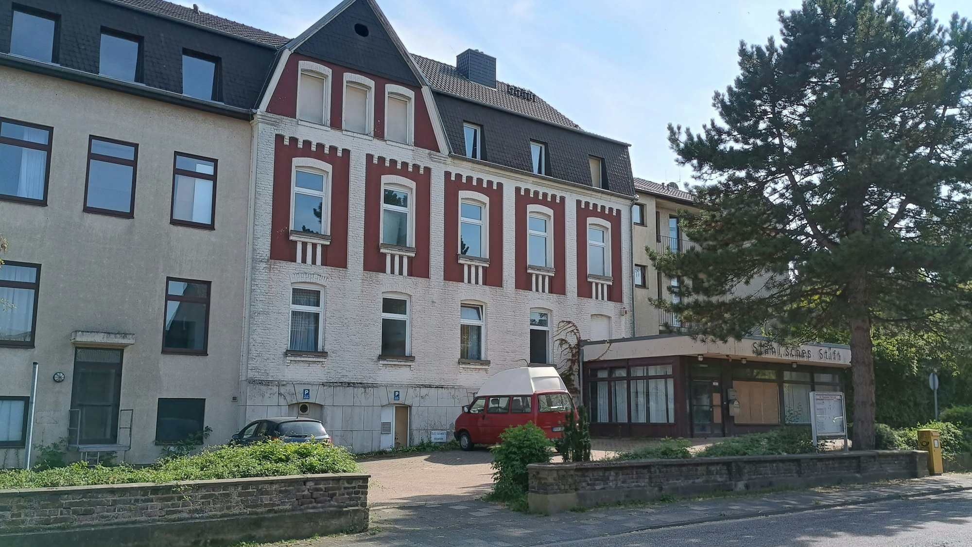 Zu sehen ist das mehrstöckige Haus, davor parken zwei Autos.