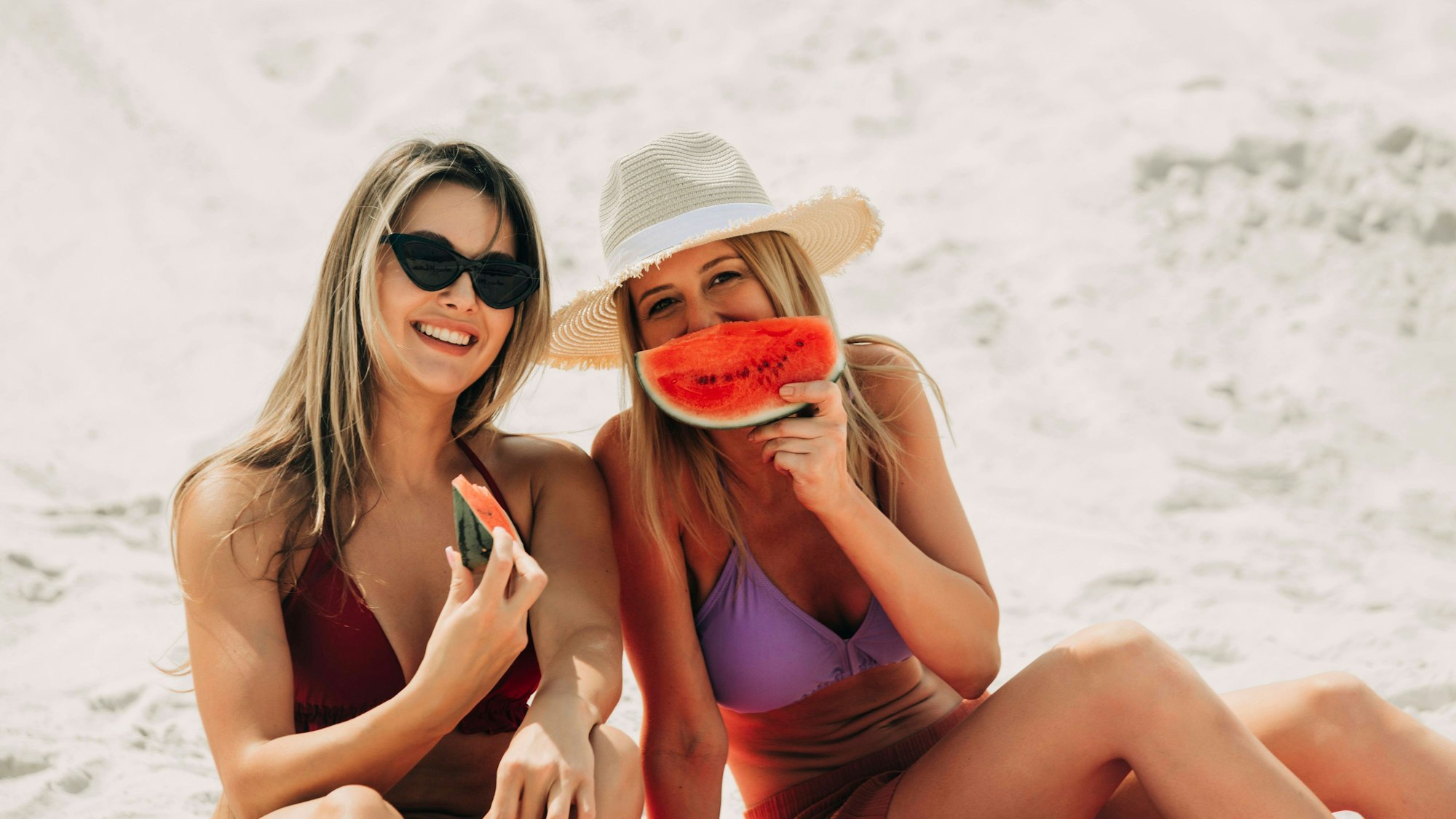 Zwei Freundinnen essen am Strand Wassermelone