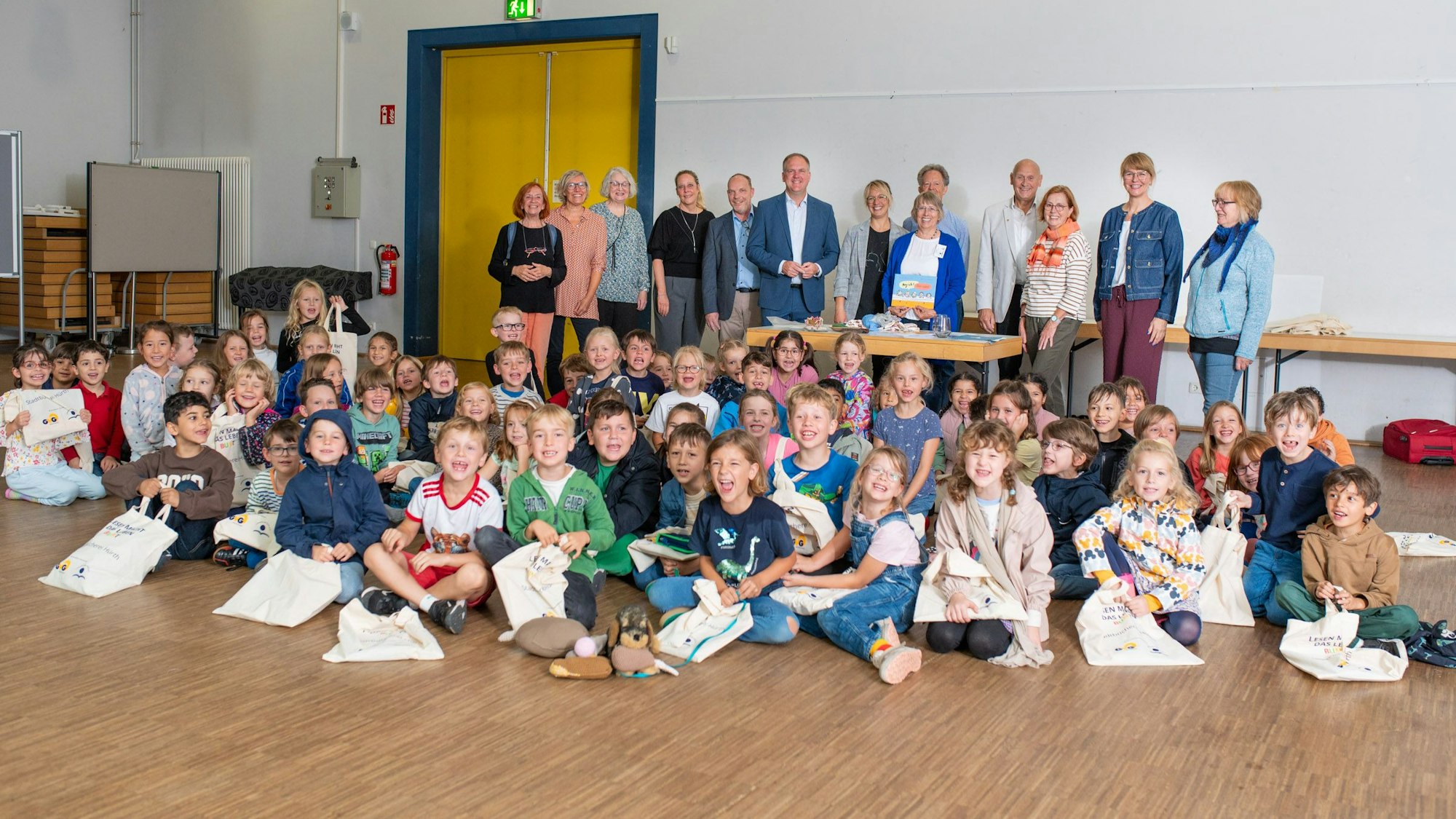 Das Foto zeigt die Schulkinder mit ihren Lesetaschen, dahinter die Vertreter der Stadt, der Leserfreunde und der Sponsoren.