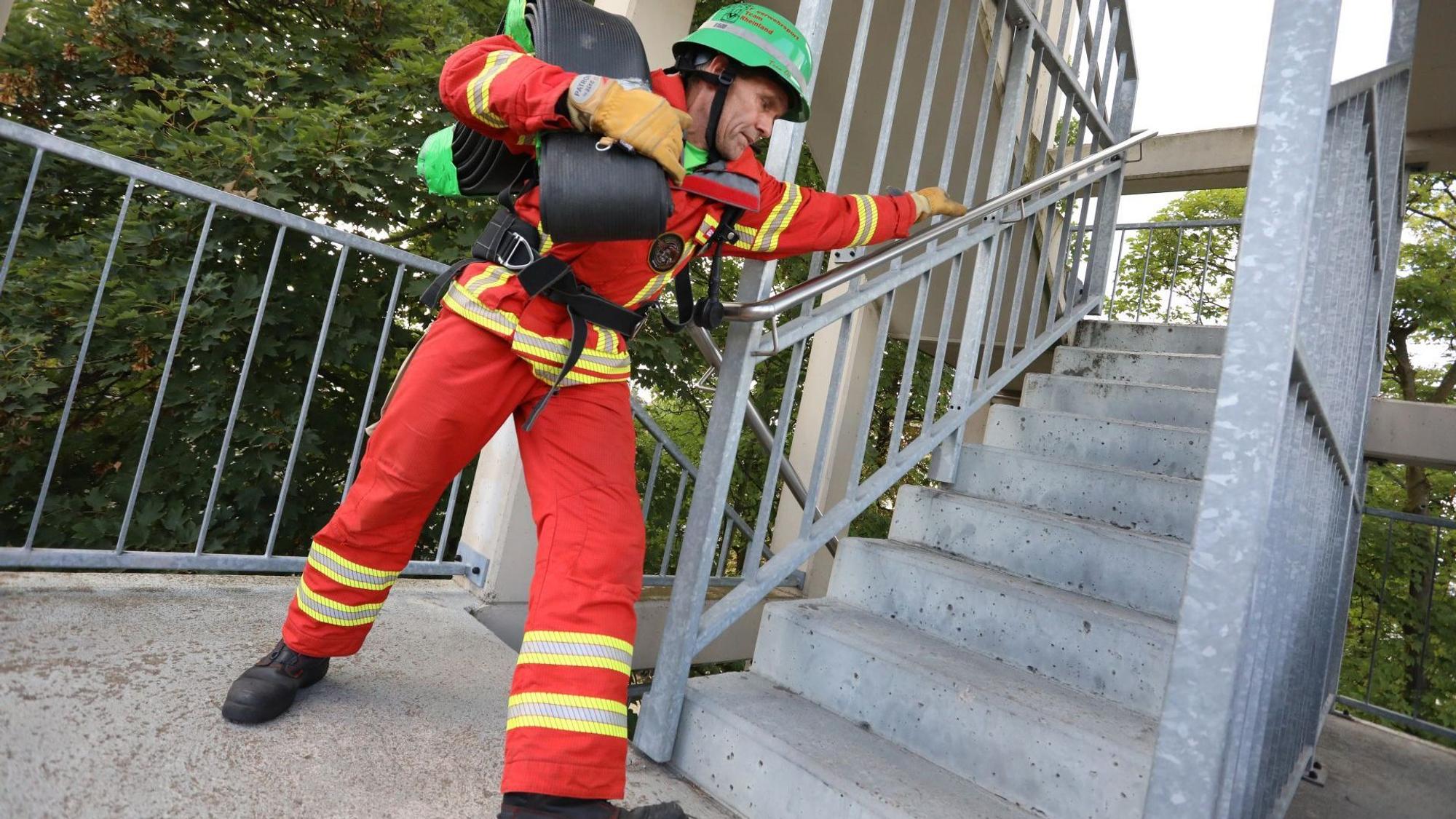 Ein Mann in roter Kleidung und mit grünem Helm läuft eine Treppe hinauf.