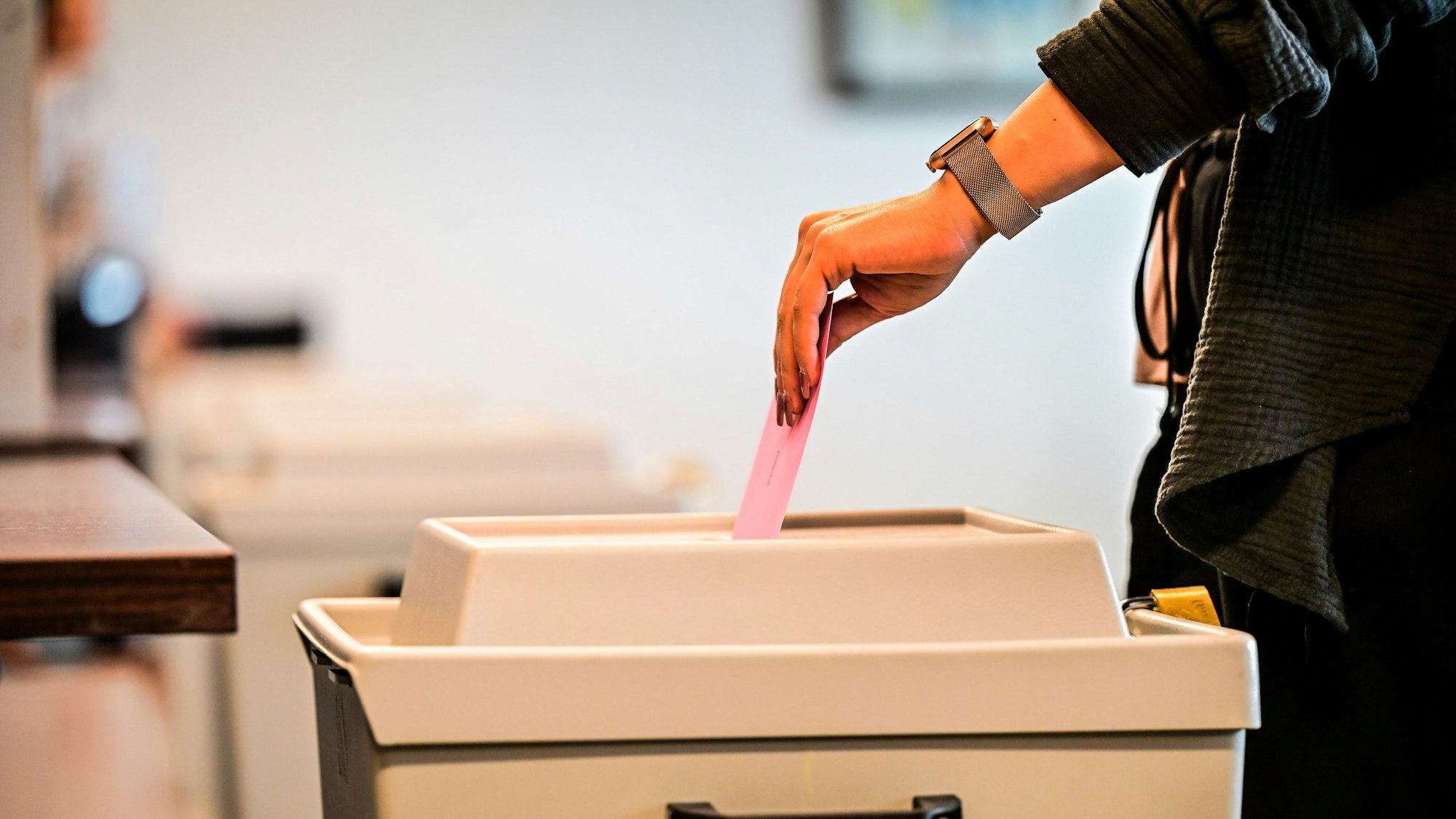 Ein Wähler wirft den Briefumschlag in die Wahlurne.