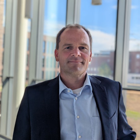 Das Foto zeigt den Amprion-Manager auf einer Treppe vor einer Glasfassade im Neubau auf dem Campus in Brauweiler