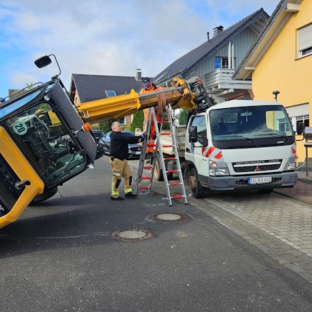 Der Hubarm eines umgekippter Radladers wird mit einer Leiter gestützt.