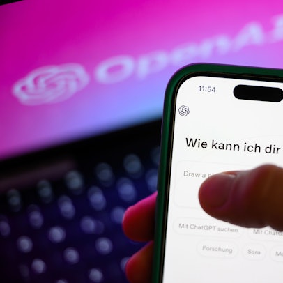 Ein Smartphone mit dem KI-Chatbot ChatGPT ist vor dem Logo des US-Softwareunternehmens OpenAI zu sehen.
