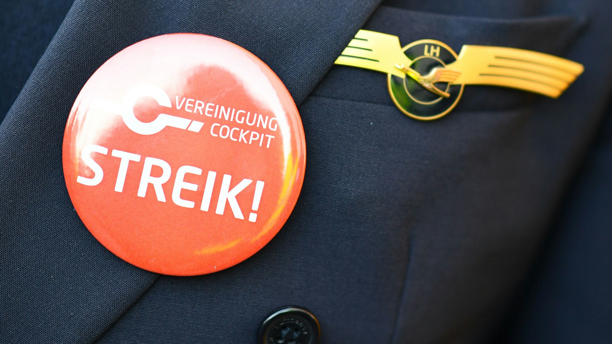 Ein Lufthansa-Pilot trägt bei einer Kundgebung der Pilotengewerkschaft Vereinigung Cockpit einen Button mit der Aufschrift „Streik!“ auf seiner Uniform. (Archivbild)
