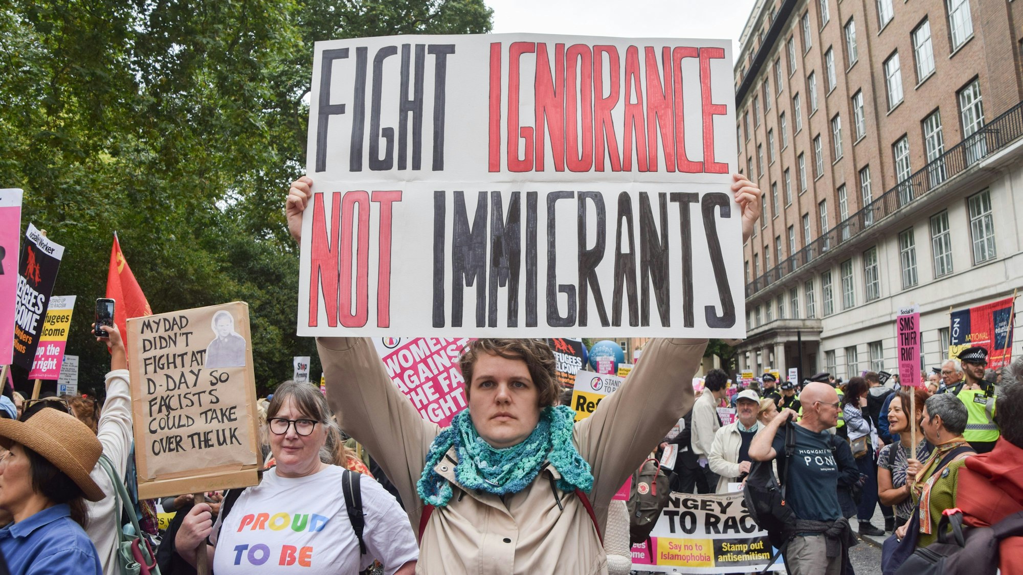 "Fight Ignorance, not Immigrants" steht auf einem Plakat, das eine Demonstrantin während einer Kundgebung gegen Rassismus und Faschismus und zur Unterstützung von Migranten hält.