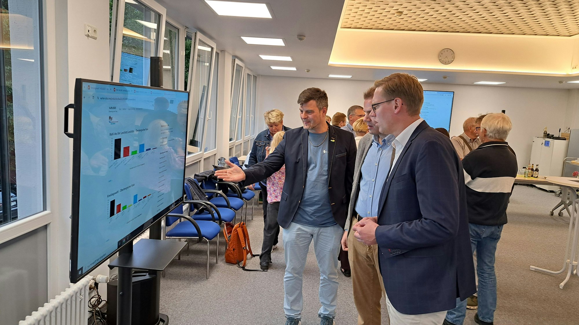 Männer beobachten Wahlergebnisse auf einem Bildschirm.
