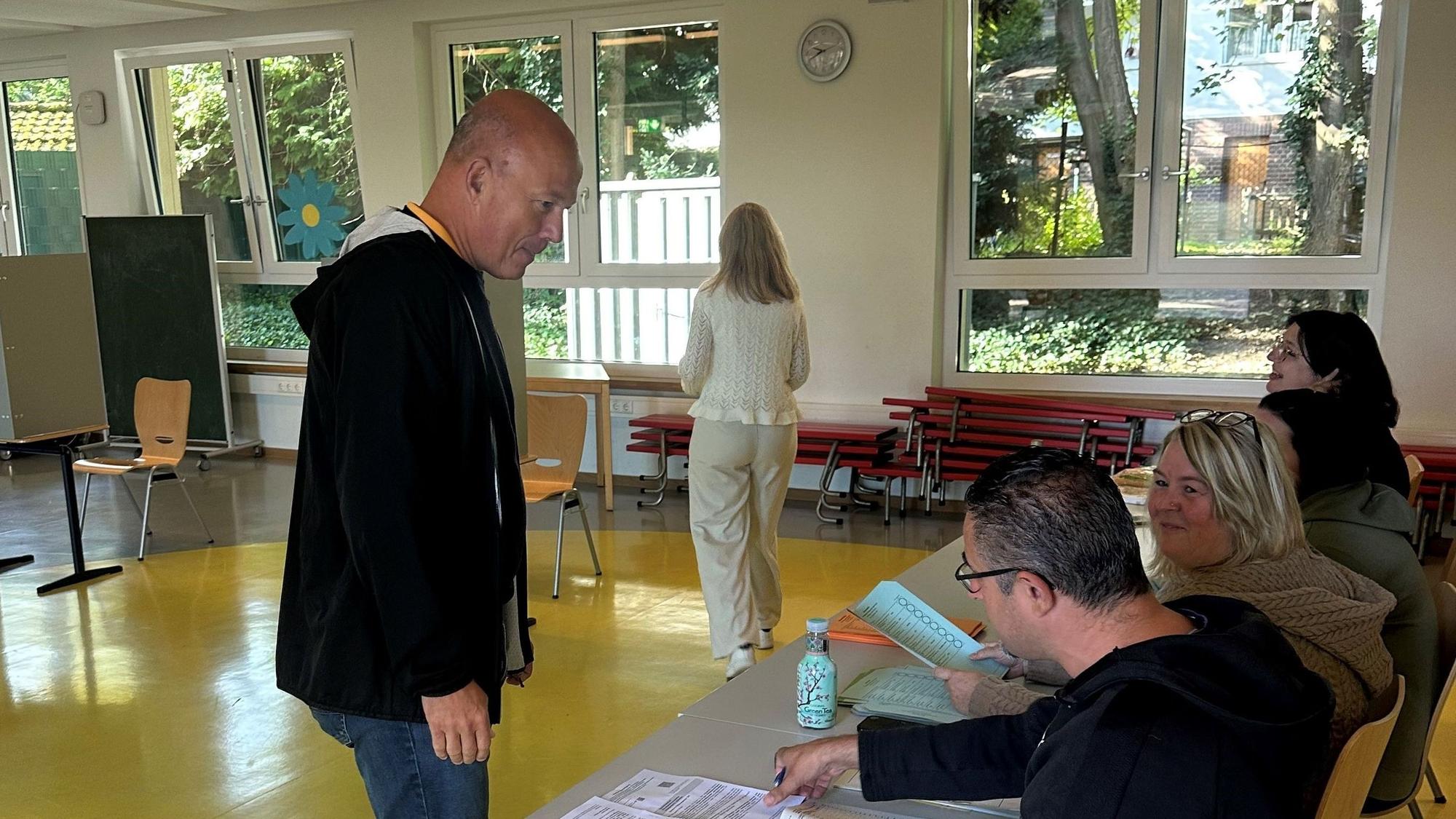Auf dem Bild sind Wähler und Wahlhelfer in einem Wahllokal zu sehen.