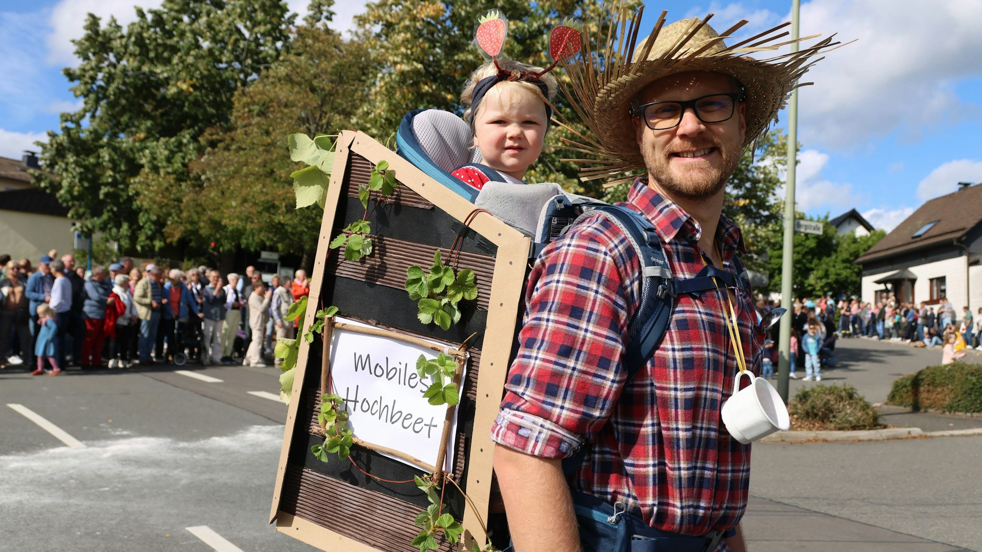 Ein Vater trägt sein Tochter auf dem Rücken in einem "mobilen Hochbeet".