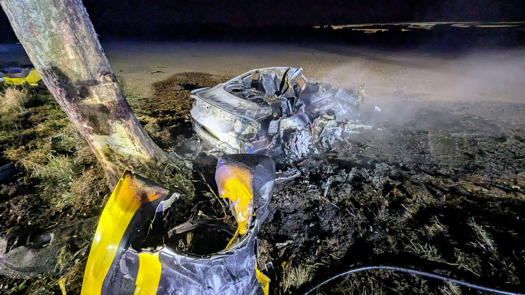 HANDOUT - 14.09.2025, Nordrhein-Westfalen, Bedburg-Hau: Trümmer eines Fahrzeugs an der Unfallstelle. Bei einem schweren Unfall im Nordwesten Nordrhein-Westfalens sind drei Menschen ums Leben gekommen. Ein Auto sei in Bedburg-Hau nahe der niederländischen Grenze nach dem Überholen von der Straße abgekommen, gegen einen Baum geprallt und habe Feuer gefangen, teilte die Polizei mit. Foto: ---/Freiwillige Feuerwehr Bedburg-Hau/dpa - ACHTUNG: Nur zur redaktionellen Verwendung im Zusammenhang mit der aktuellen Berichterstattung und nur mit vollständiger Nennung des vorstehenden Credits +++ dpa-Bildfunk +++