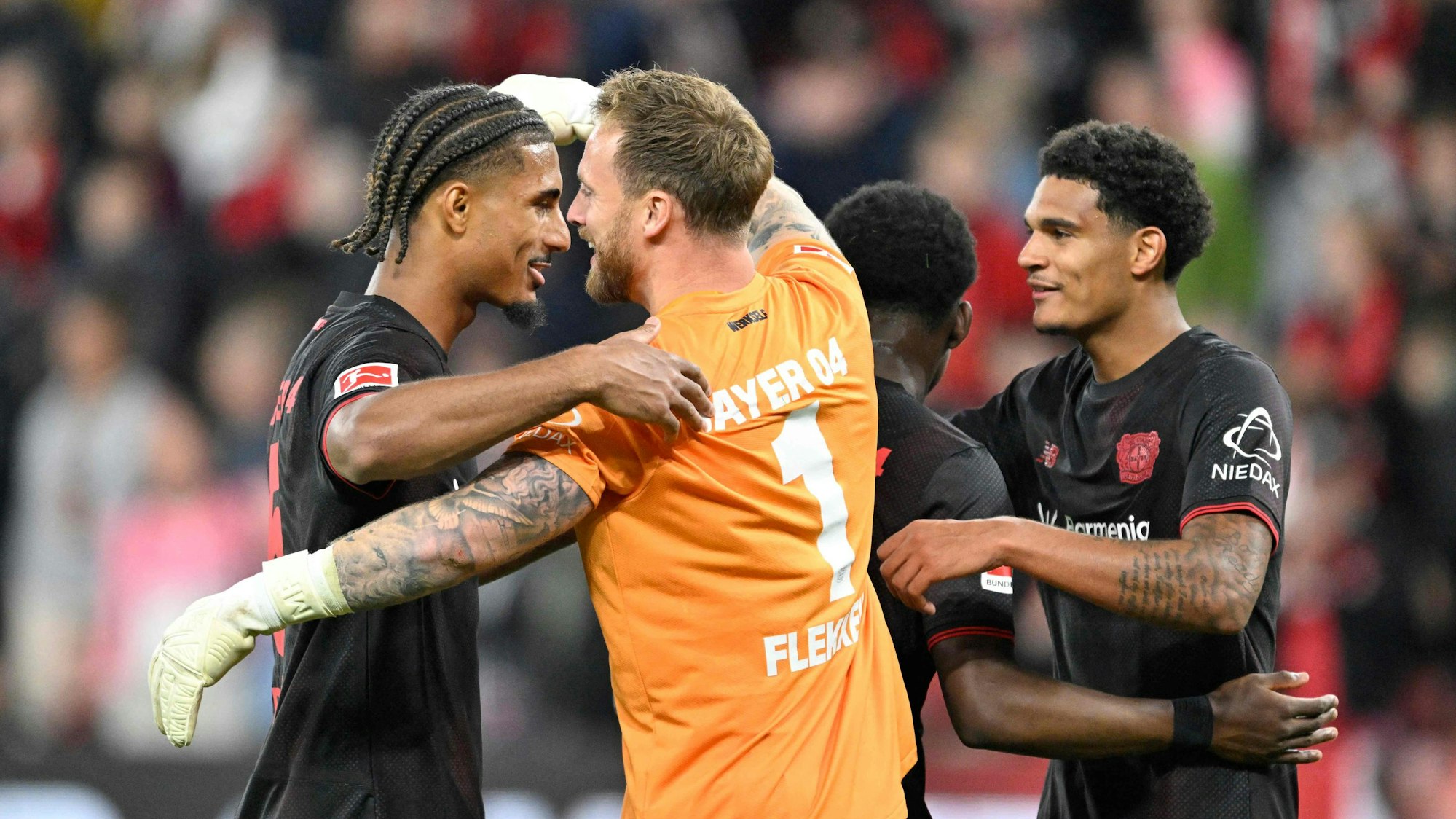 Leverkusens Spieler Loic Badé (v.li.), Mark Flekken, Axel Tape und Jarell Quansah nach dem Sieg gegen Eintracht Frankfurt.