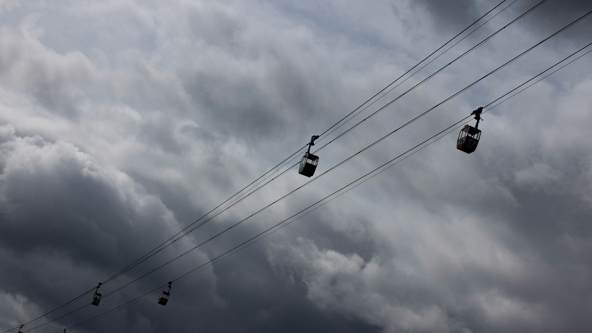 Eine Seilbahn ist vor dunklen Wolken am Himmel zu sehen (Symbolfoto).