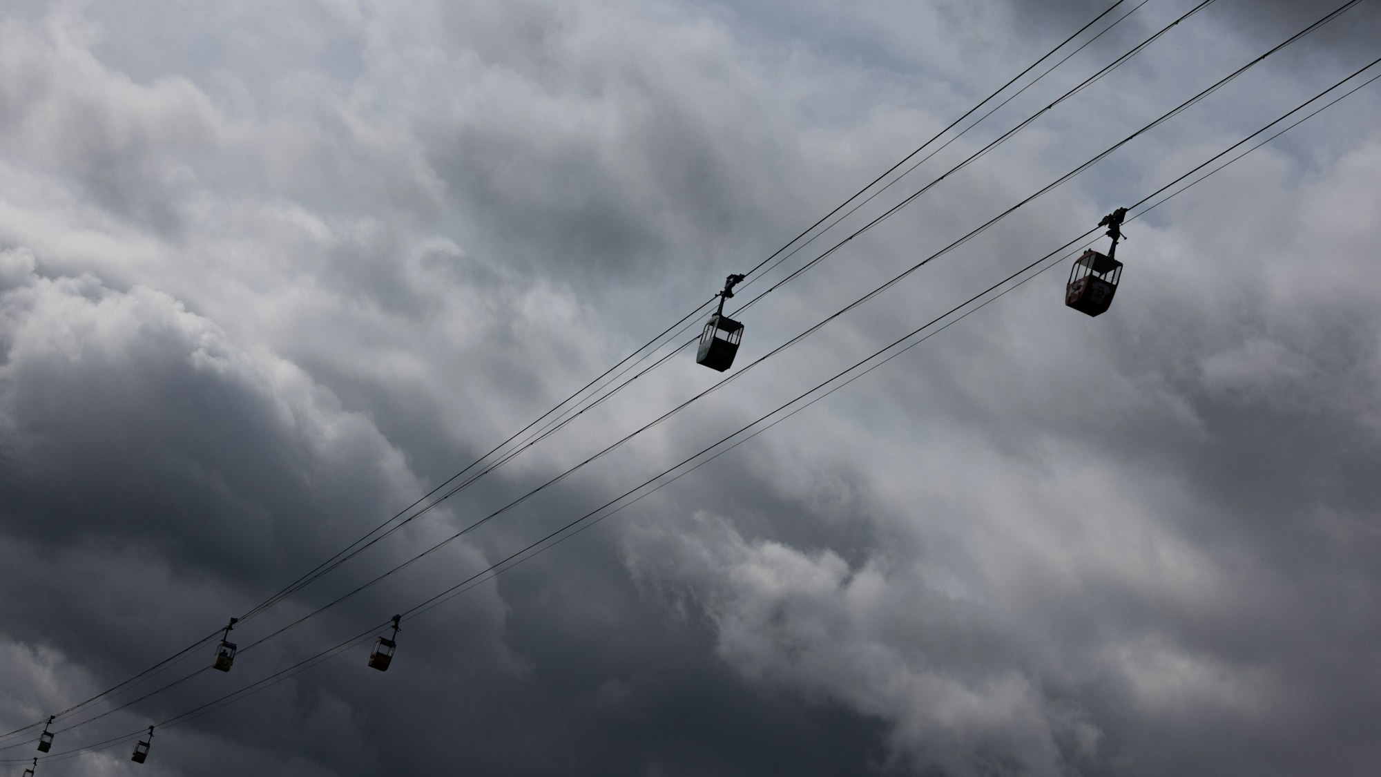 Die Seilbahn über den Rhein ist vor dunklen Wolken am Himmel zu sehen.