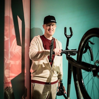 Roman Arnold, Gründer und langjähriger Geschäftsführer des Fahrradbauers Canyon aus Koblenz hält den Lenker eines Rennrads fest und lächelt in die Kamera.