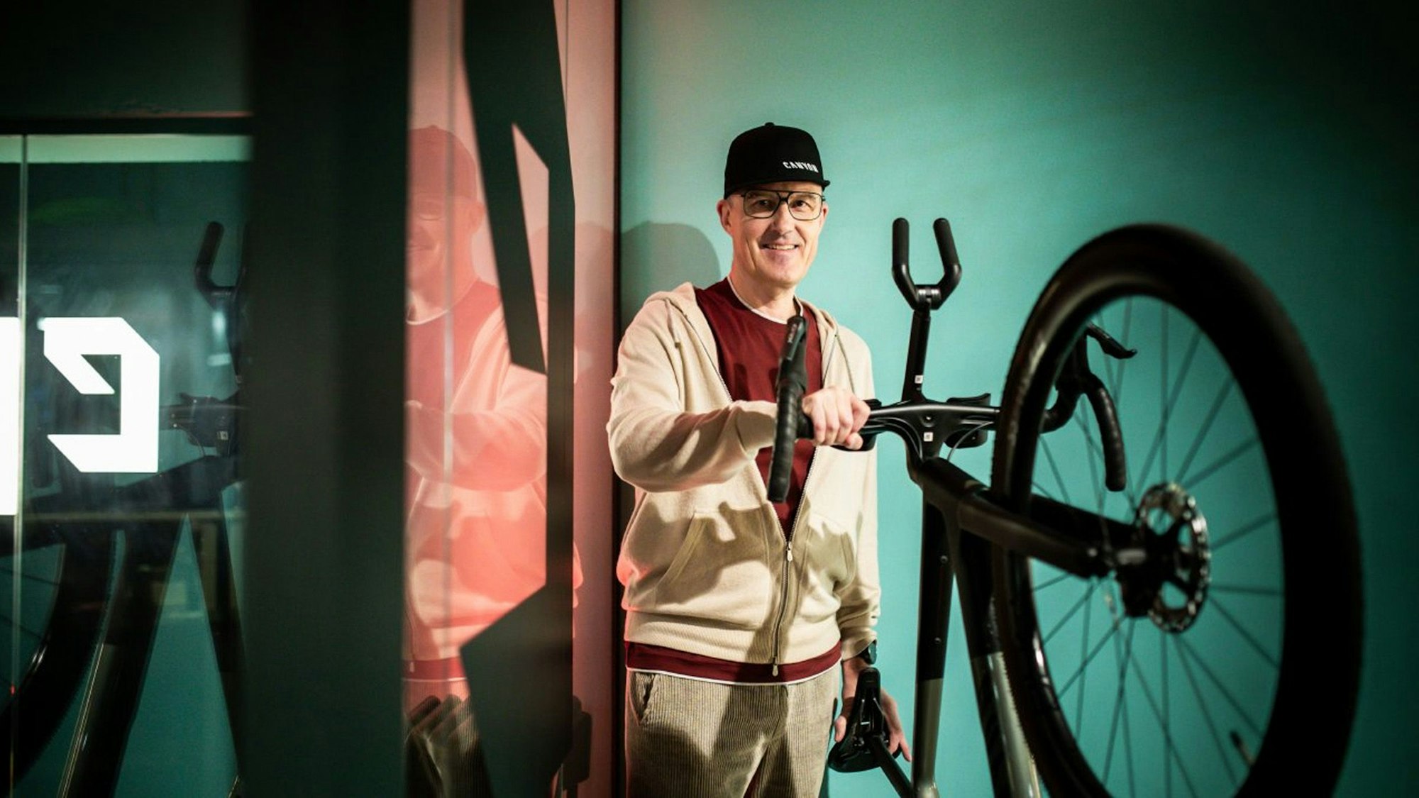 Roman Arnold, Gründer und langjähriger Geschäftsführer des Fahrradbauers Canyon aus Koblenz hält den Lenker eines Rennrads fest und lächelt in die Kamera.