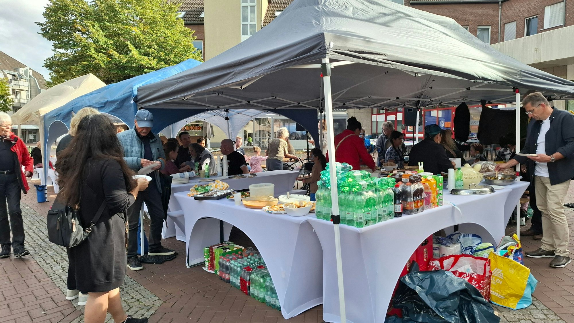Menschen stehen an einem Stand mit Getränken und Essen.