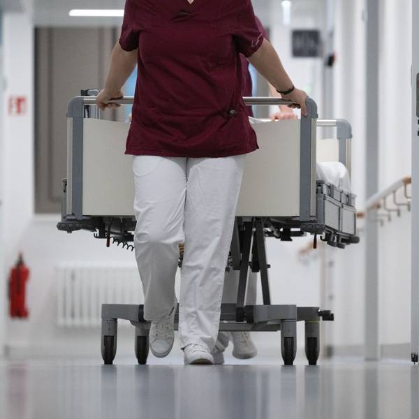 Eine Krankenpflegerin und ein Krankenpfleger schieben ein Krankenbett durch den Gang einer Station eines Krankenhauses (Symbolbild)