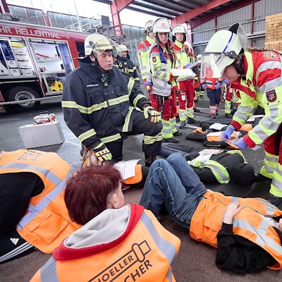Jugendliche Darsteller, denen Verletzungen angeschminkt wurden, liegen auf dem Boden und werden von Sanitätern und Feuerwehrleuten versorgt.