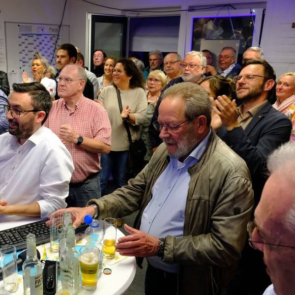 Zahlreiche Menschen stehen bei einer Wahlparty im Mechernich Rathaus in einem Raum.