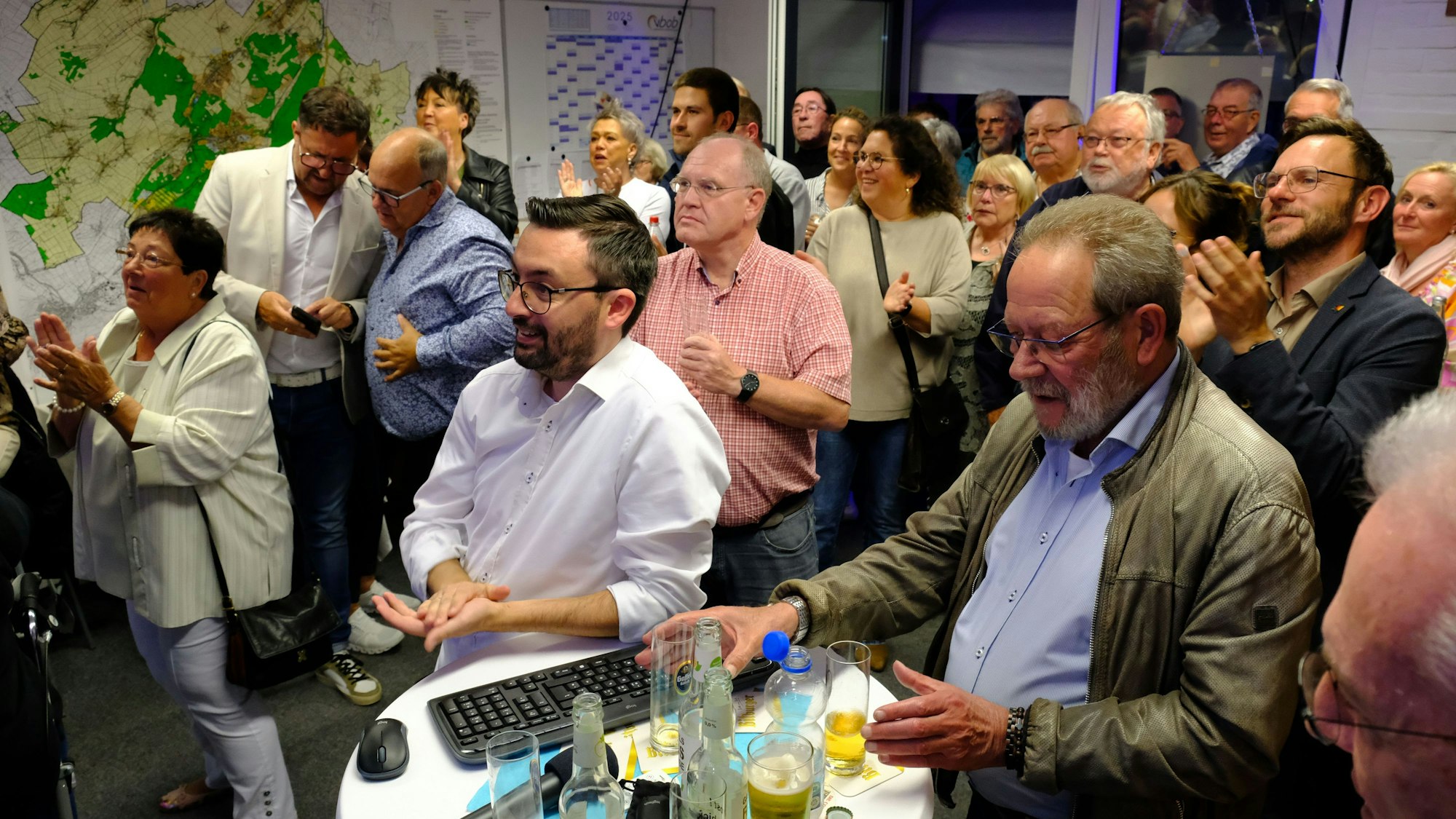 Zahlreiche Menschen stehen bei einer Wahlparty im Mechernich Rathaus in einem Raum.