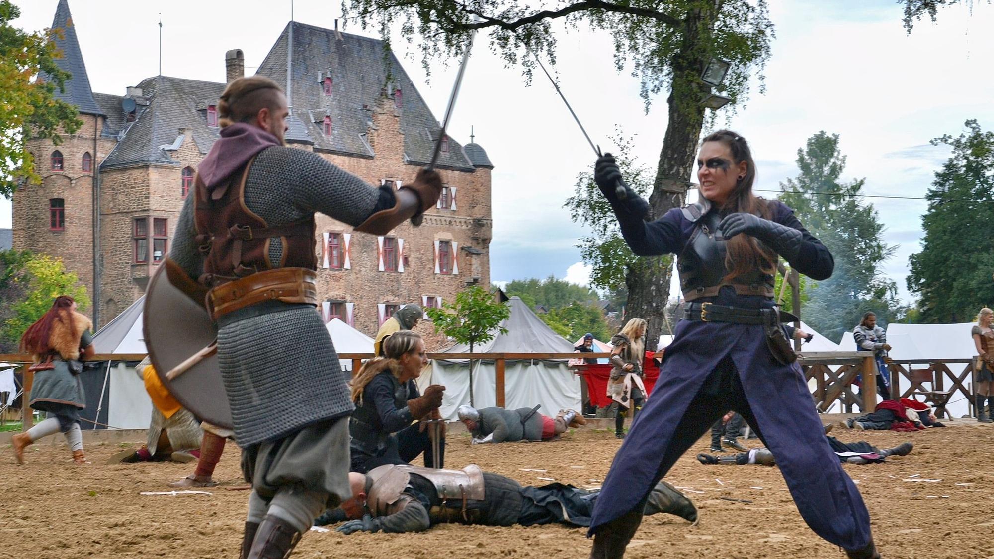 Bei den Ritterspielen auf Burg Satzvey kämpfen eine Frau und ein Mann mit Schwertern gegeneinander.