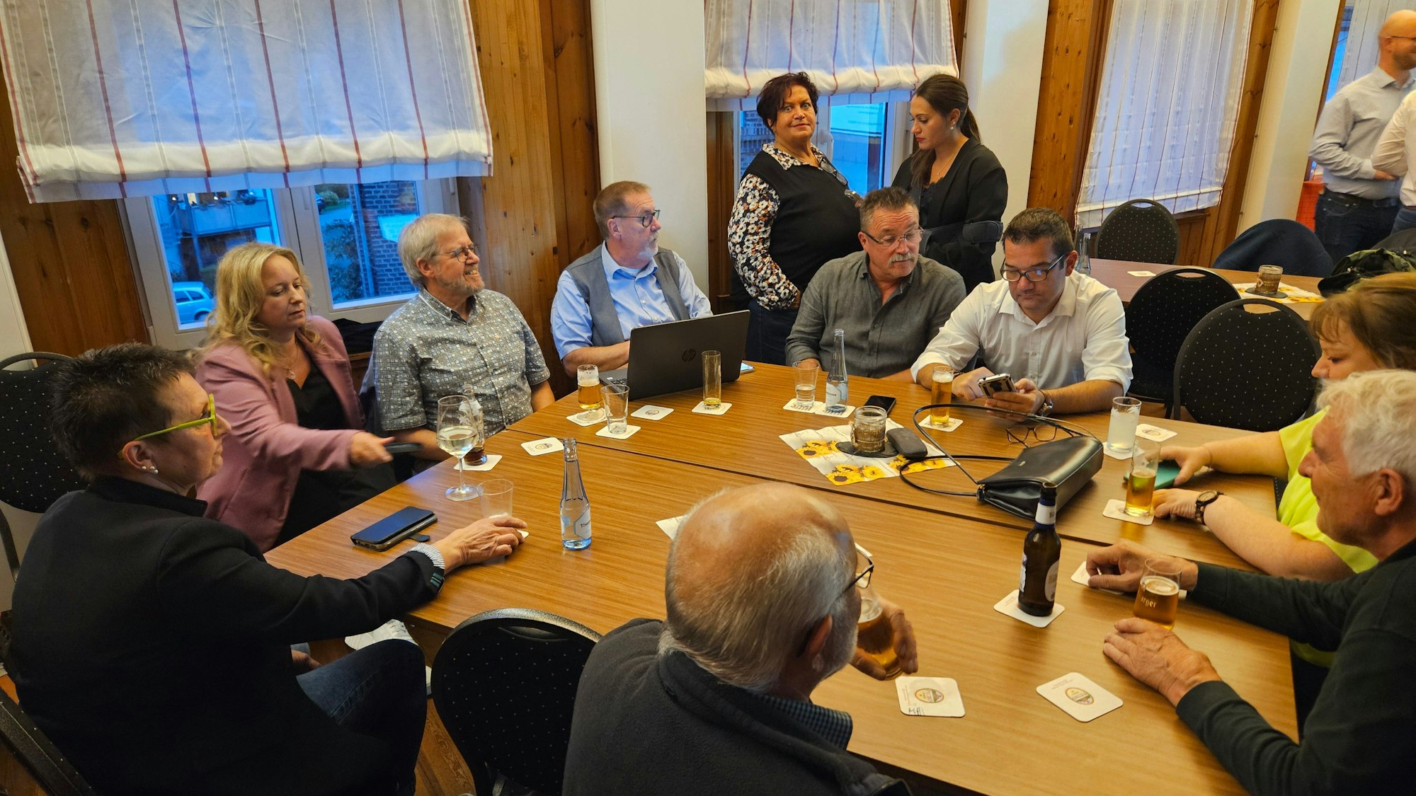 Männer und Frauen der Kaller CDU sitzen an Tischen und schauen zum Teil in ihre Handys.