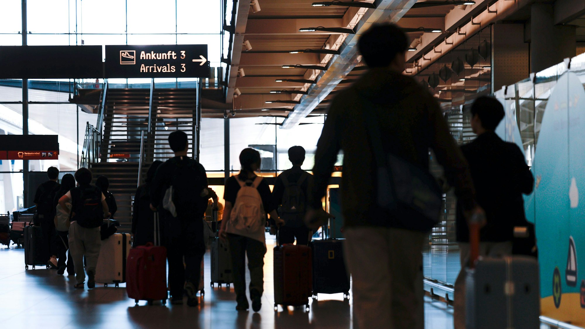 24.08.2025, Nordrhein-Westfalen, Köln: Flugreisende ziehen nach der Landung mit ihren Trolleys durch den Ankunftsbereich des Flughafens Köln/Bonn. In Nordrhein-Westfalen enden an diesem Wochenende die Schulferien. Foto: Thomas Banneyer/dpa +++ dpa-Bildfunk +++