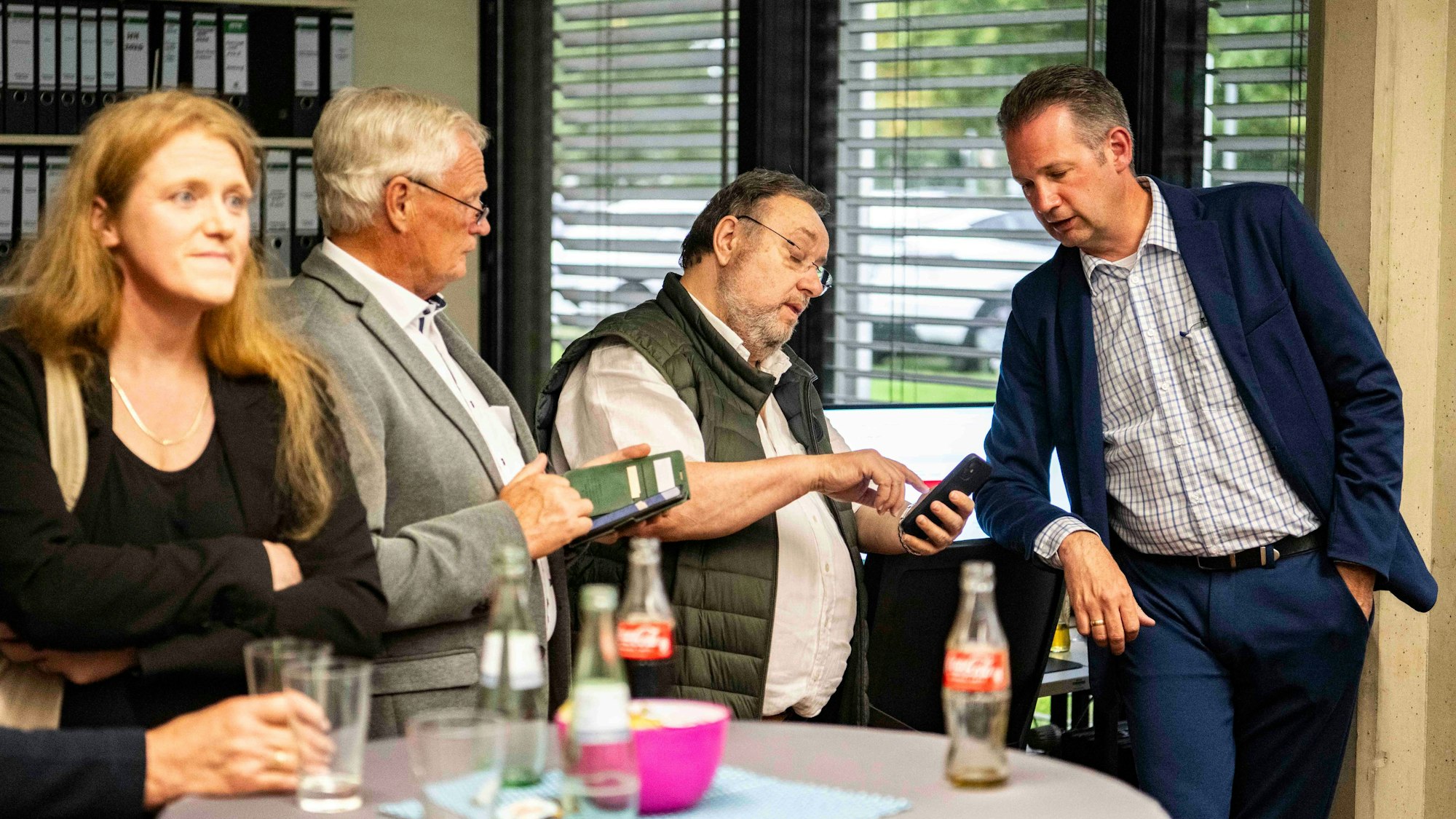 Das Bild zeigt Politiker, die teilweise auf ihr Handy schauen.