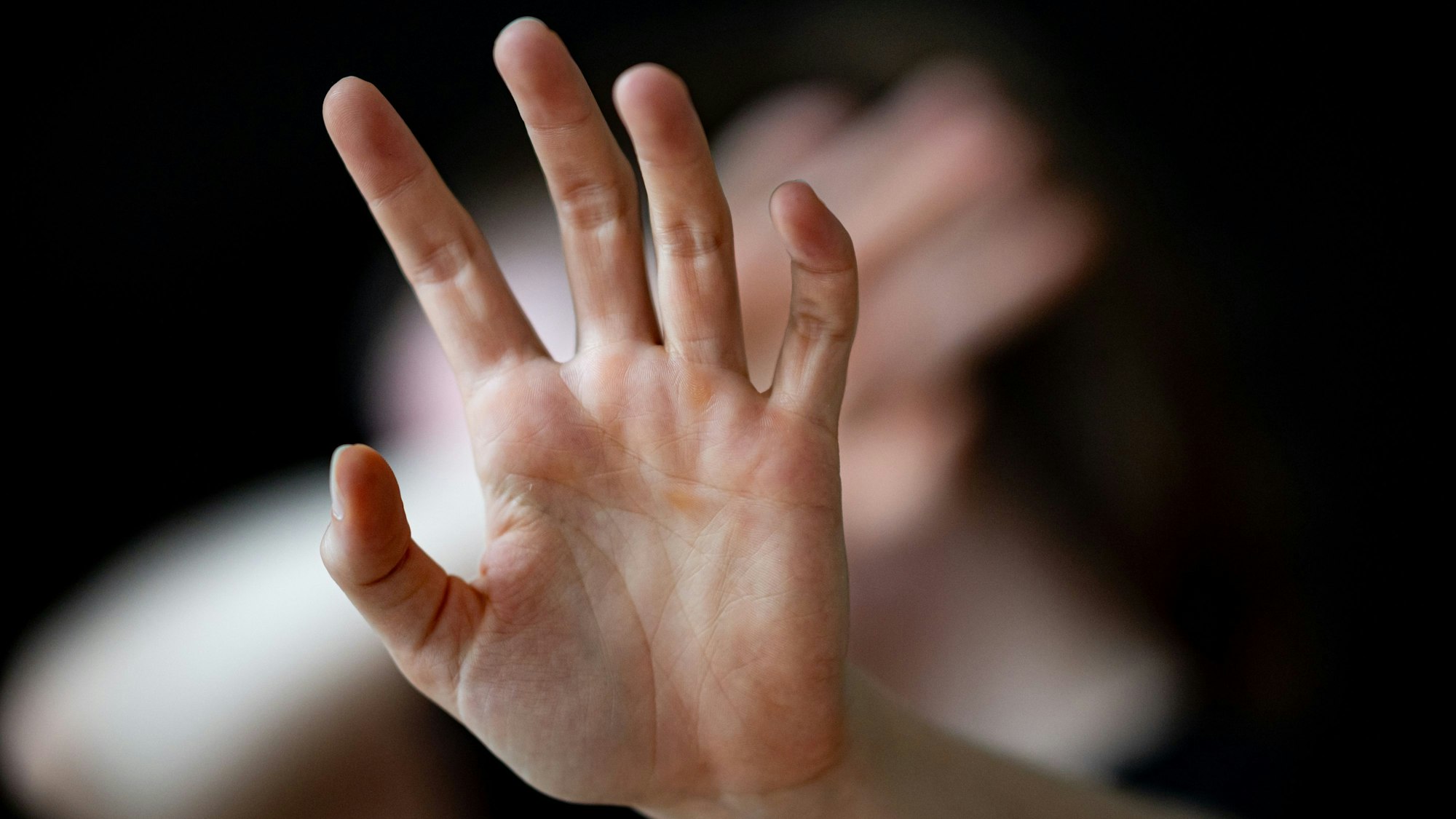 Eine Frau hält ihre Hände vor das Gesicht.