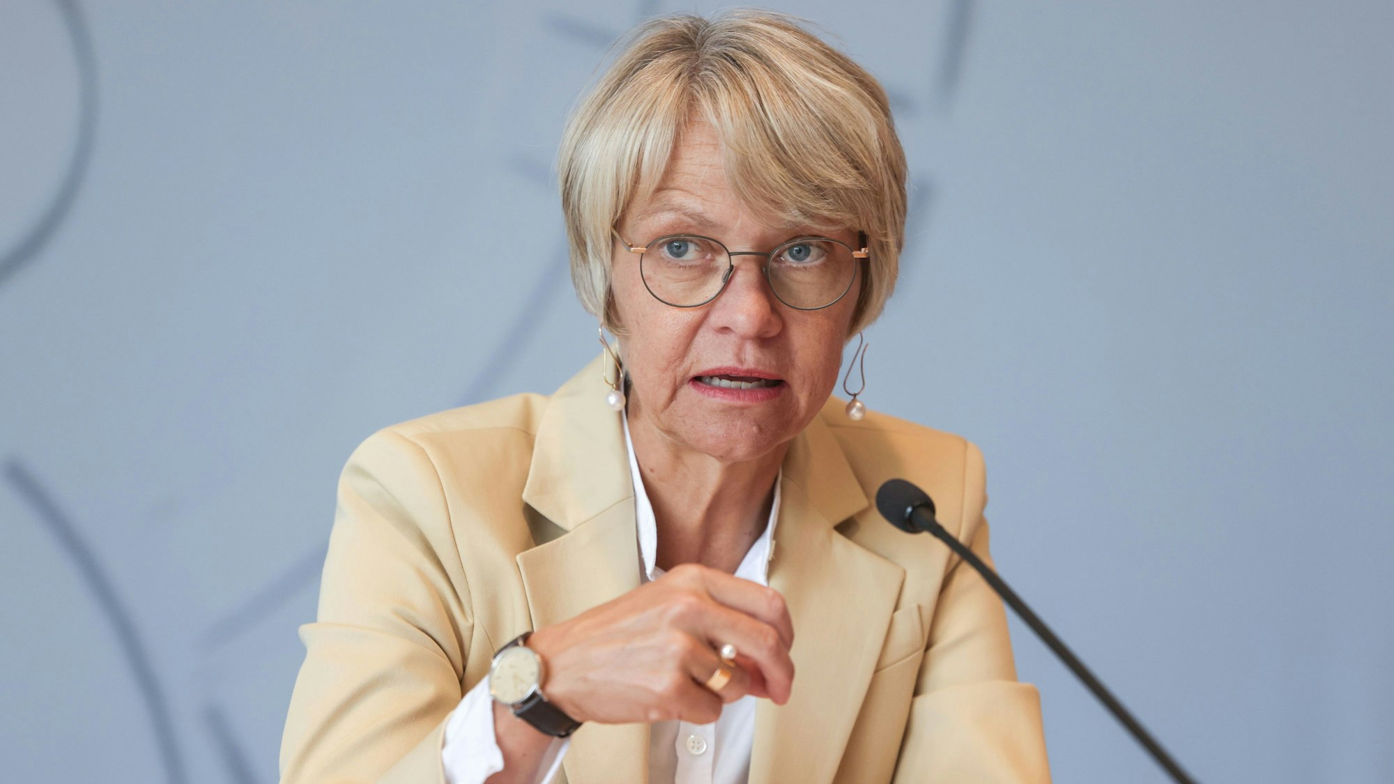 NRW-Schulministerin Dorothee Feller (CDU) spricht vor einem Mikrofon. Ihre rechte Hand unterstützt ihre Aussage gestisch. Sie trägt eine weiße Bluse und einen cremefarbenen Blazer.