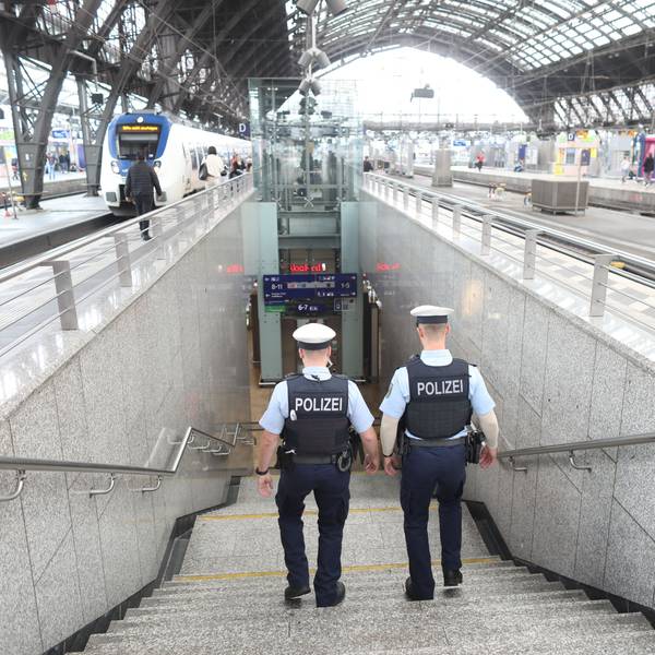 Zwei Bundespolizisten laufen im Kölner Hauptbahnhof eine Treppe hinab. Im oberen Bereich ist das Dach des Bahnhofs zu erkennen.