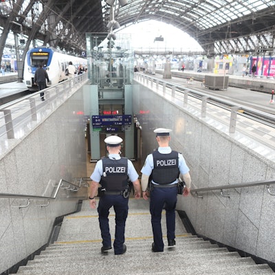 Zwei Bundespolizisten laufen im Kölner Hauptbahnhof eine Treppe hinab. Im oberen Bereich ist das Dach des Bahnhofs zu erkennen.