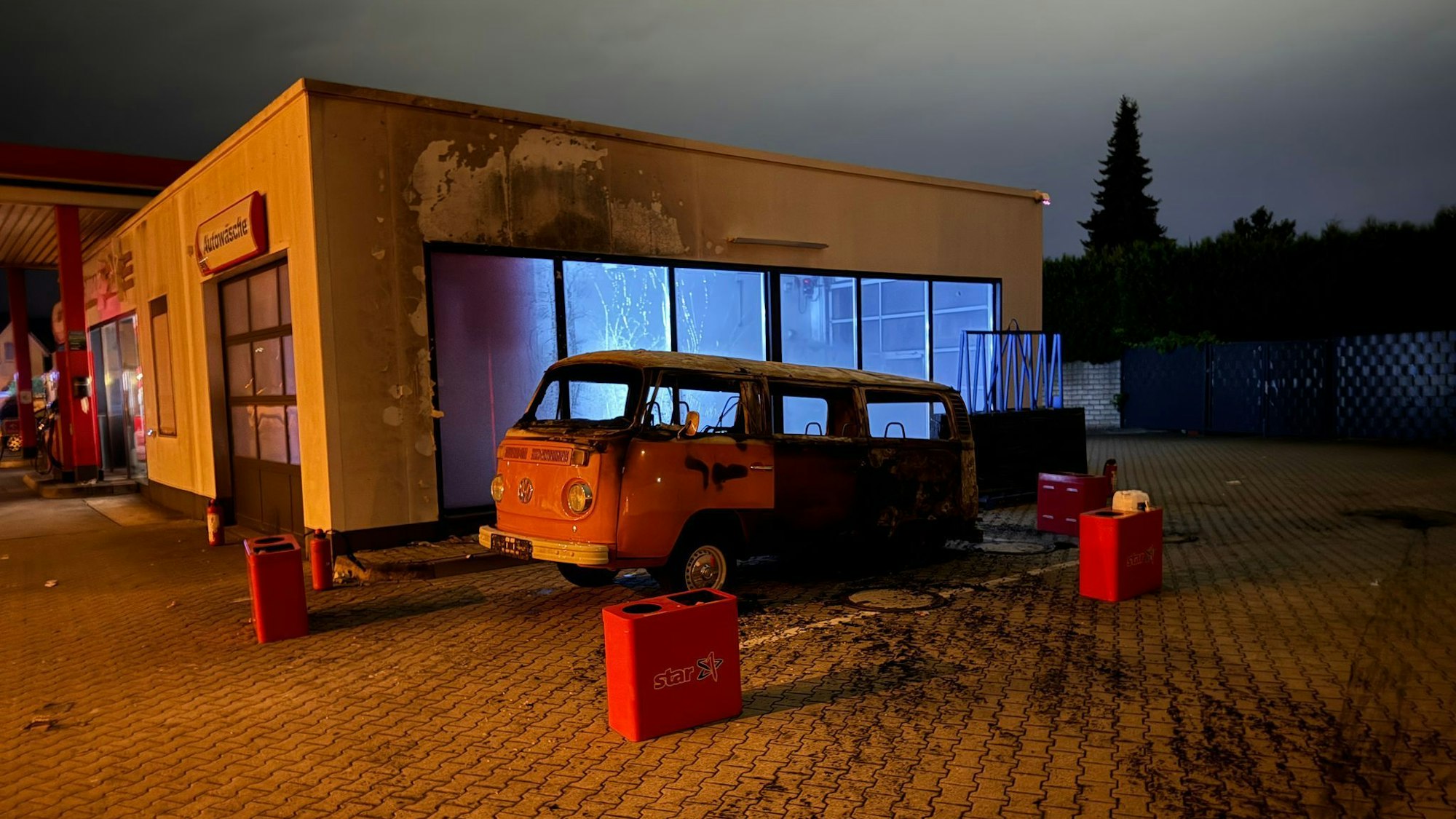 Der ausgebrannte VW Bus an der Star-Tankstelle in Porz-Grengel.
