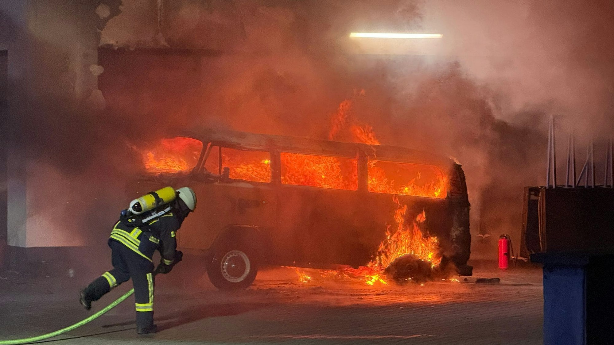 Die Feuerwehr löscht den brennenden VW Bus auf dem Gelände der Tankstelle am Akazienweg, Ecke Waldstraße.