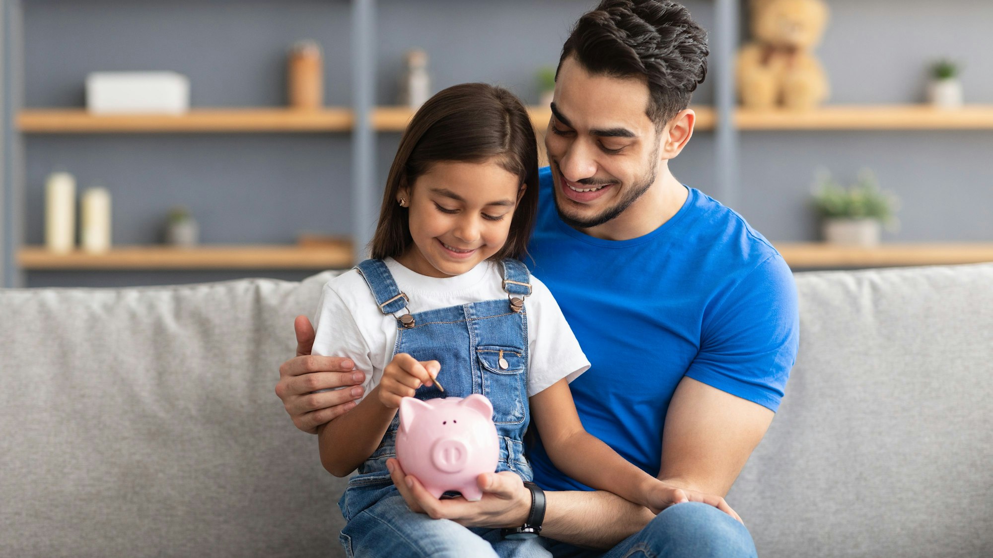 Vater und Tochter füttern gemeinsam das Sparschwein.
